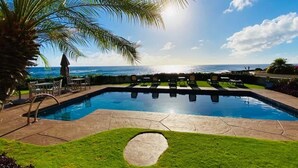 Ein Pool mit Liegestühlen und Blick aufs Meer.