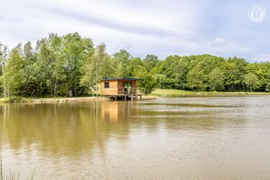 Situated over a serene body of water, this cabin offers a tranquil retreat surrounded by lush greenery.