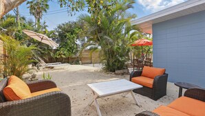 An outdoor patio with wicker furniture, a white table, and a blue wall. - Coco Sands Studios (Cocoa Beach)