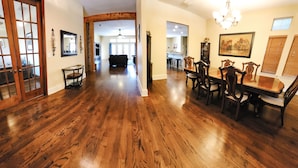 A spacious hallway with hardwood floors, a dining area with wooden chairs and a table, and a kitchen in the background. - Huge 4 bedroom + loft lakehouse with private dock - 27 min north of Sundance Sq  (Fort Worth)