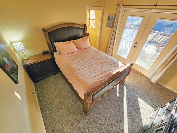 Un dormitorio con cama, mesita de noche, cómoda y puerta que da a un balcón.