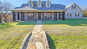A two-story house with a stone facade, a covered porch, and a stone pathway leading to the entrance. - Huge 4 bedroom + loft lakehouse with private dock - 27 min north of Sundance Sq  (Fort Worth)