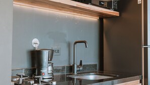 A modern kitchen with wooden cabinetry, a stainless steel refrigerator, a built-in microwave, a coffee maker, and a sink. - Cost-effective enjoyable Studio in Laureles with A/C (Medellín)