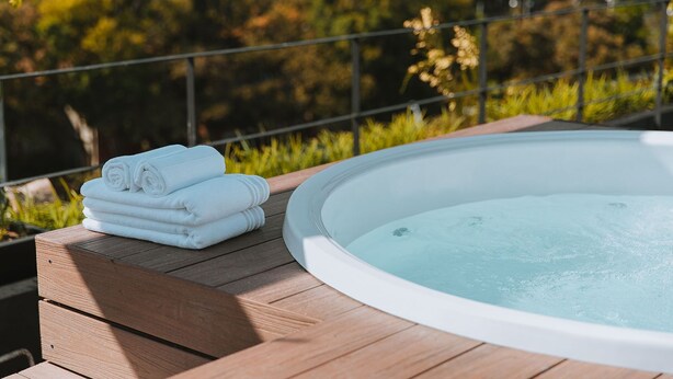 A hot tub on a wooden deck with a railing, surrounded by greenery. - Cost-effective enjoyable Studio in Laureles with A/C (Medellín)
