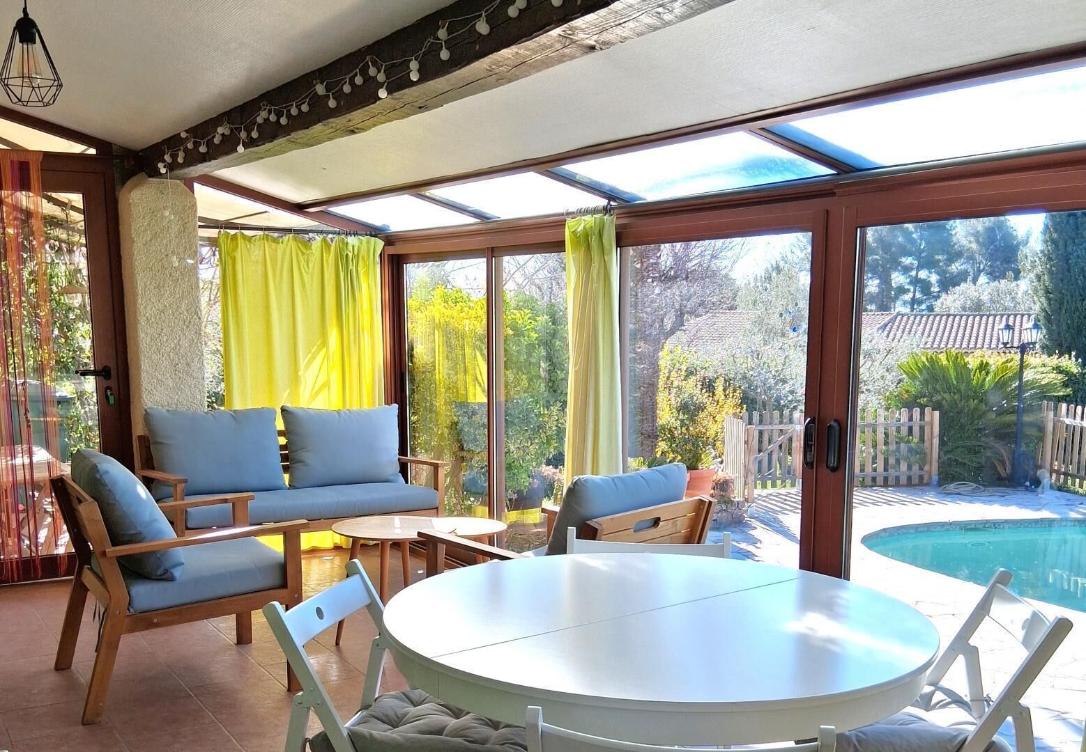 A sunlit patio with a round table, two sofas, and a pool view.