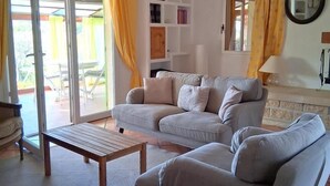 A living room with a sofa, a wooden coffee table, and a patterned rug. - Gîte de Font du Roux (FLAYOSC)