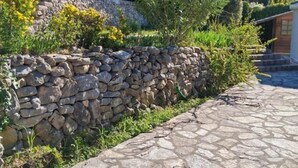A stone wall with a stone pathway leading to a building. - Gîte de Font du Roux (FLAYOSC)