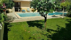 Una piscina con sillas de descanso, un área de césped y un edificio al fondo.