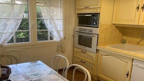Una cocina con dos hornos, un lavabo y una ventana con cortinas de encaje.