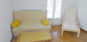 A living room with a beige sofa, two yellow cushions, a wooden coffee table, and a white armchair.