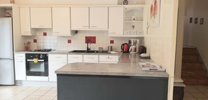 A modern kitchen with white cabinets, a built-in oven, a coffee maker, and a kettle.