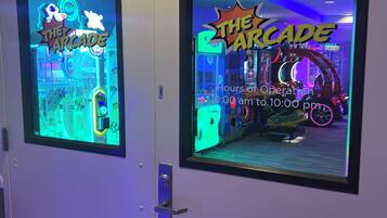 Twee speelhalruimtes met neonborden, elk met de tekst 'The Arcade' en 'Openingstijden van 10:00 tot 22:00.'