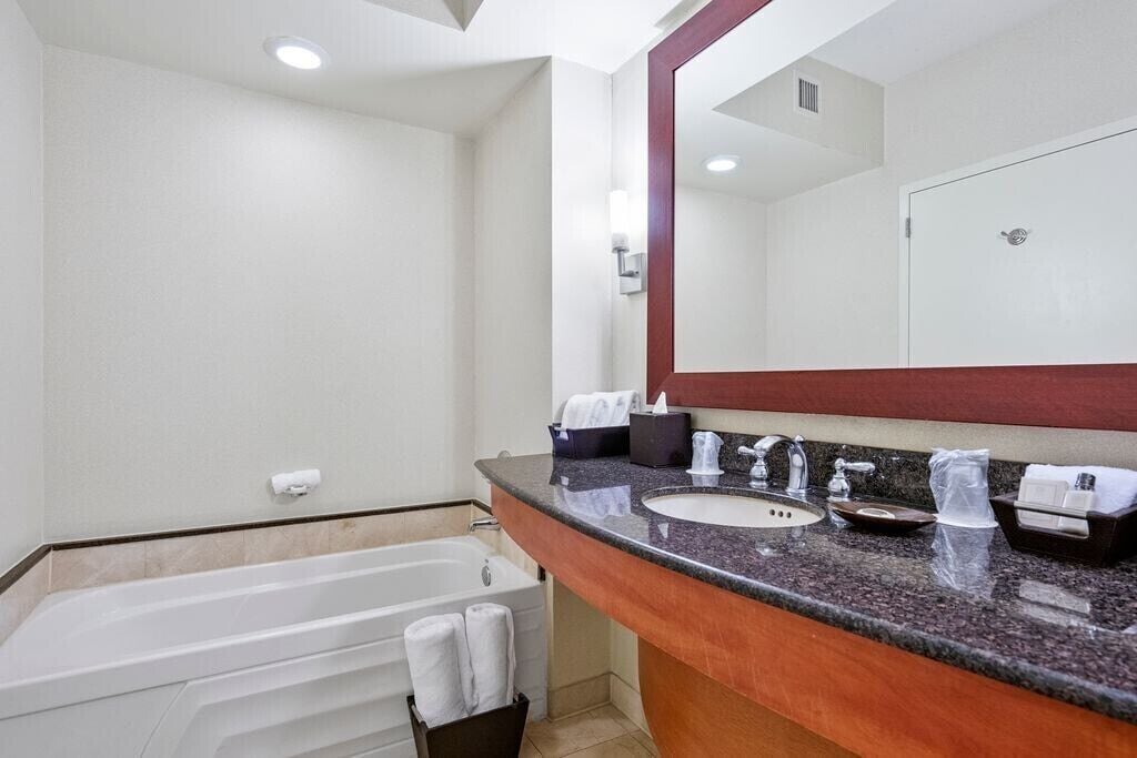 A modern bathroom with a bathtub, a sink, and a large mirror.