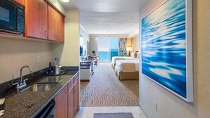 Una habitación de hotel con cocina, un ventanal grande y un cuadro en la pared.