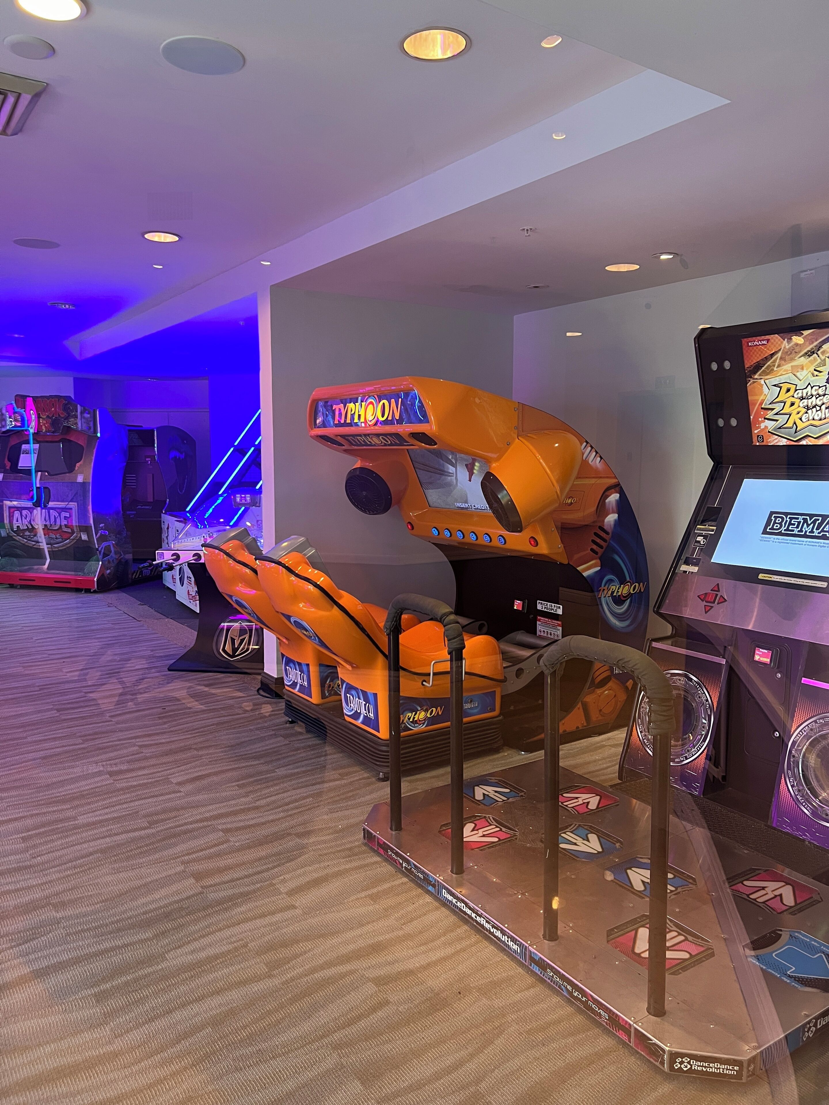 A dance arcade with a prominent 'Typhoon' game machine, other arcade games, and a carpeted floor.
