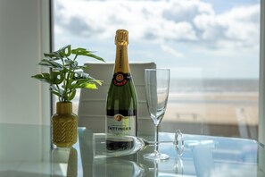 A bottle of Taittinger champagne and a glass on a table with a view of the beach.