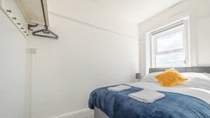 A bedroom with a bed, a window, and a coat rack. - Highcliffe Seaview Suite (Blackpool)