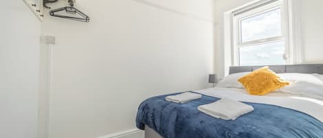 Une chambre à coucher avec un lit, une fenêtre et un porte-manteau.