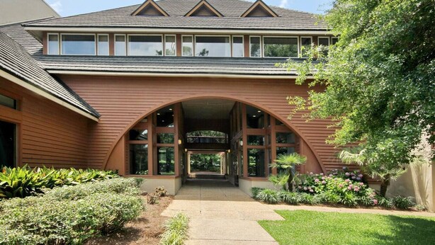 A two-story building with a prominent arched entrance, large windows, and a sloped roof. - LakeViews-Quaint/Quiet-Wlk 2 Beach-Kingston Plantation-Gated Community (Myrtle Beach)