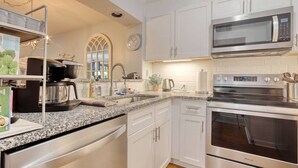 A modern kitchen with stainless steel appliances, a granite countertop, and white cabinetry. - LakeViews-Quaint/Quiet-Wlk 2 Beach-Kingston Plantation-Gated Community (Myrtle Beach)