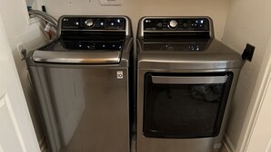 Une buanderie équipée de deux lave-linge et deux sèche-linge à chargement frontal en acier inoxydable.