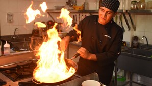 Un chef cuisinant avec des flammes dans une cuisine.