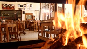 Un coin repas avec des meubles en bois et un feu de cheminée en premier plan.