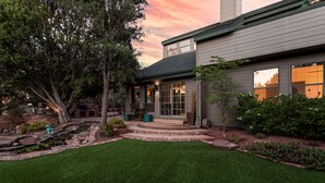 A modern house with a well-maintained lawn, a stone pathway leading to the front door, and a large tree to the left.