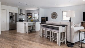 A modern kitchen with white cabinetry, stainless steel appliances, and a central island with stools. - Ocean View! 100 steps to feet in the sand! Super Clean! (Jacksonville Beach)