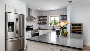 A modern kitchen with stainless steel appliances, white cabinetry, and a central island. - Ocean View! 100 steps to feet in the sand! Super Clean! (Jacksonville Beach)