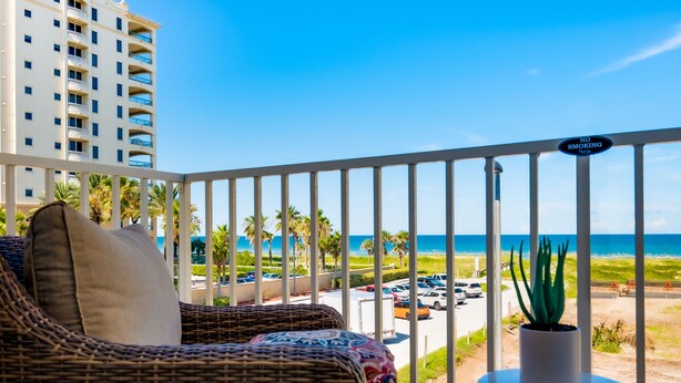 A balcony with wicker furniture, a potted plant, and a 'No Smoking' sign. - Ocean View! 100 steps to feet in the sand! Super Clean! (Jacksonville Beach)