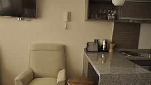 Une cuisine moderne dotée d’un îlot central intégré, d’un téléviseur à écran plat fixé au mur, d’un téléphone et d’une machine à café.