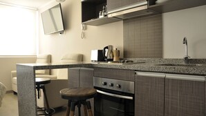 Une cuisine moderne dotée de plans de travail en granit, d’un four encastré, d’une machine à café et d’un tabouret de bar.