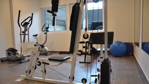 Une salle de sport équipée de divers appareils d’entraînement, notamment un banc de développé couché, des haltères et des ballons d’exercice.