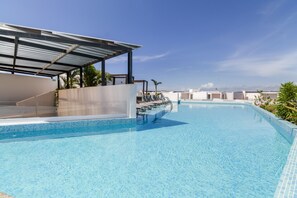 Une piscine dotée d’un espace couvert et de chaises longues.