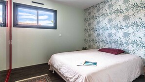 A bedroom with a bed, a window, and a patterned wall.