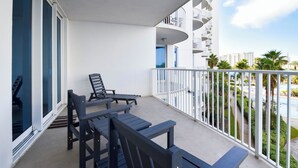 Un balcon avec une table et des chaises, une balustrade et une vue sur des palmiers et des immeubles.