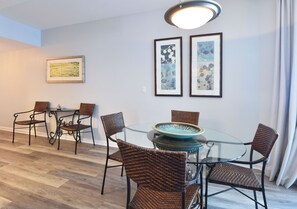 A dining area with wicker chairs, a glass table, and framed artwork on the wall. - 4th Floor condo at The Palms of Destin with Seasonal Beach Shuttle! (Destin)