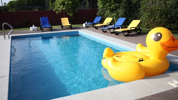 A swimming pool with inflatable duck floats and lounge chairs.