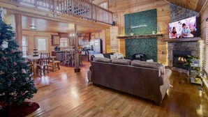 A spacious living area with a fireplace, a television, and a Christmas tree.