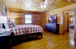 Une chambre dans une cabane en bois, avec un lit, une commode et un téléviseur.