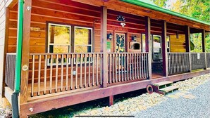 A wooden cabin with a porch, a welcome sign, and a map of the area.