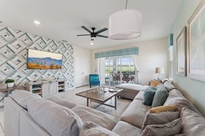 A modern living room with a sofa, coffee table, and a TV mounted on the wall.