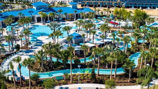 Vista aérea de un resort con varias piscinas, palmeras y edificios del complejo.
