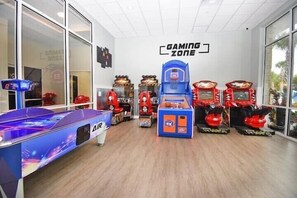 Un espace de jeux équipé d’une table de billard, de bornes d’arcade et d’un panneau indiquant « ESPACE DE JEUX ».