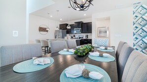 Un comedor moderno con una mesa de madera oscura, individuales color aguamarina y un arreglo floral central.