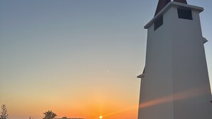 Un quartier résidentiel situé sur la côte, avec des bâtiments blancs et un ciel dégagé au coucher du soleil.