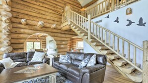 A log cabin interior with a wooden staircase, leather sofas, and a wall mural of birds. - Mountain Retreat w/ Deck: Ski, Soak, Golf & Hike! (Glenwood Springs)