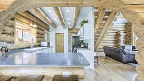 A log cabin interior with a central island, wooden beams, a kitchen area, and a seating area. - Mountain Retreat w/ Deck: Ski, Soak, Golf & Hike! (Glenwood Springs)