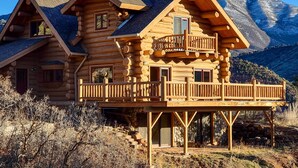 A log cabin with a balcony, multiple windows, and a stone foundation. - Mountain Retreat w/ Deck: Ski, Soak, Golf & Hike! (Glenwood Springs)